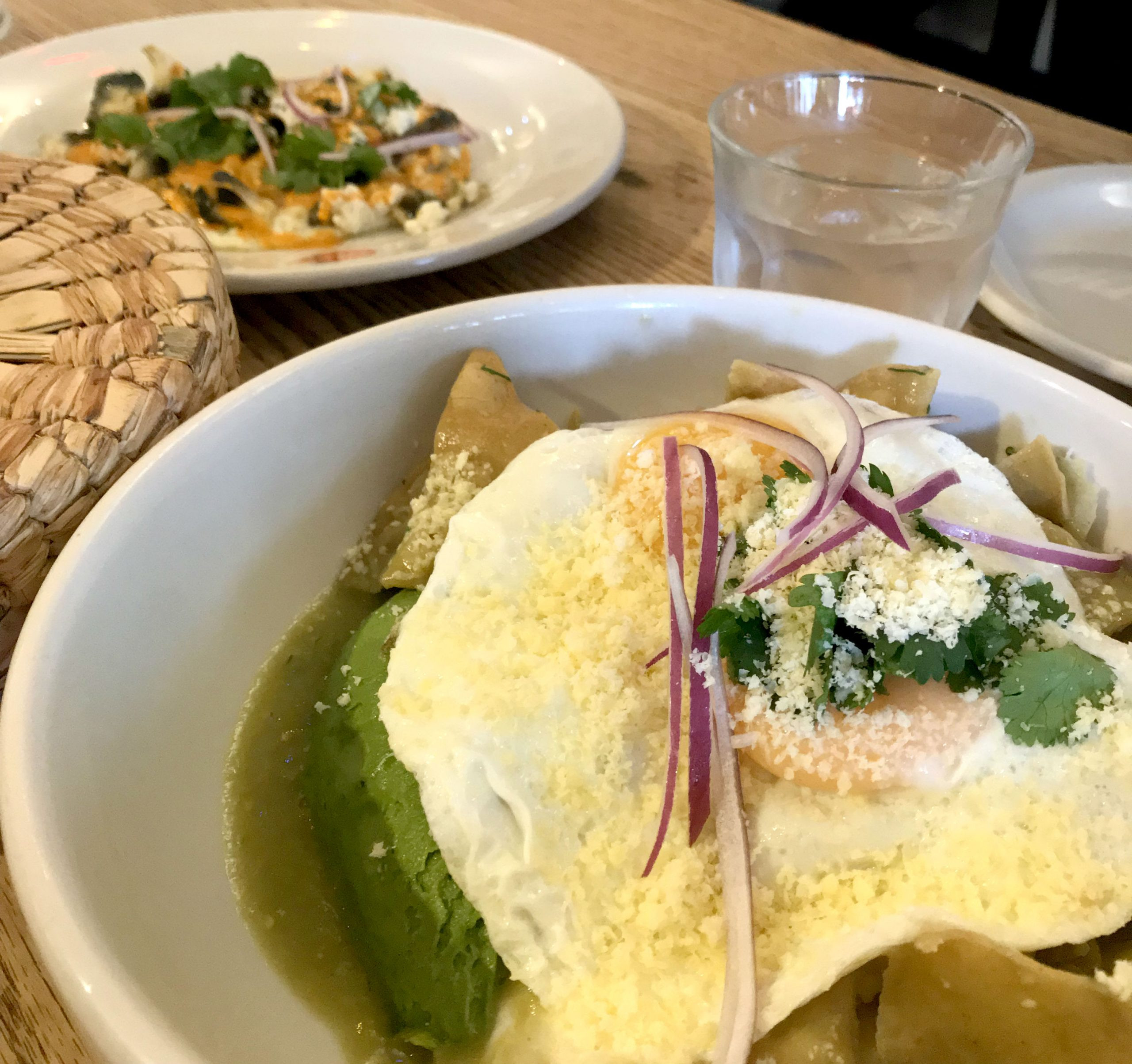 Chilaquiles, a popular Mexican breakfast dish, topped with cream, cheese, and onions