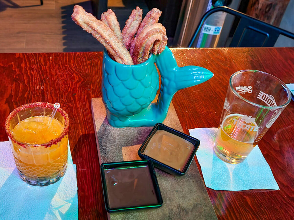 Drinks and dessert at a restaurant. The dessert is fresh, sugary churros in a bowl shaped like a fish.
