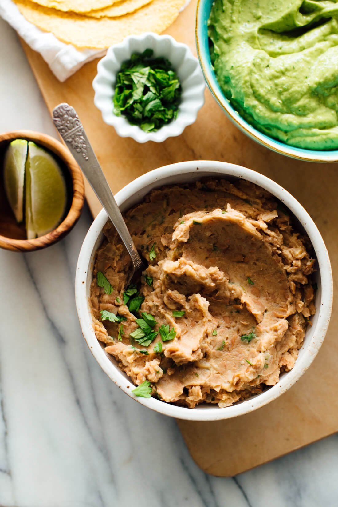 A close up of refried beans being mashed with a potato masher in a pot