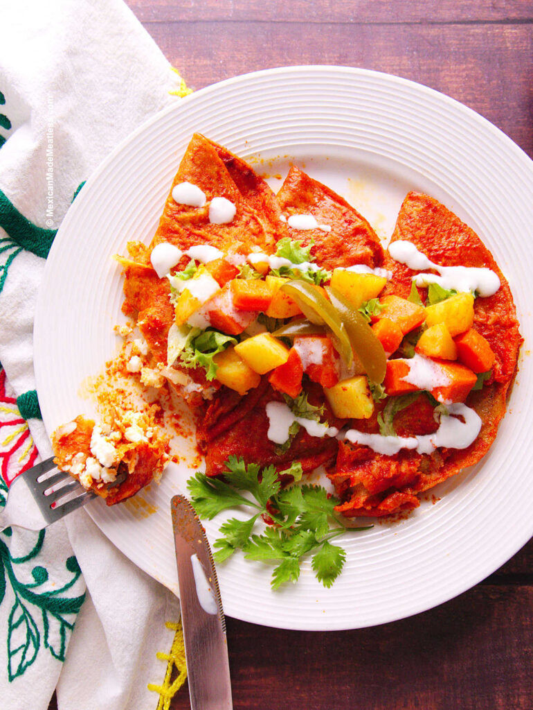 Red enchiladas filled with crumbled Mexican cheese, showcasing a classic Mexican dish that pairs perfectly with spicy pickled carrots.