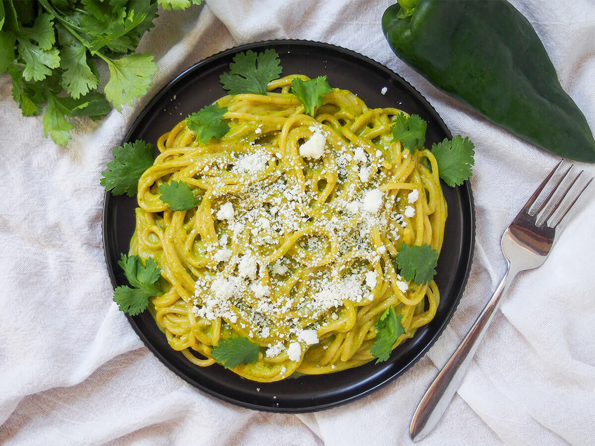 A plate of Espagueti Verde, Mexican green spaghetti, showcasing the vibrant green sauce and the comforting appeal of the dish.