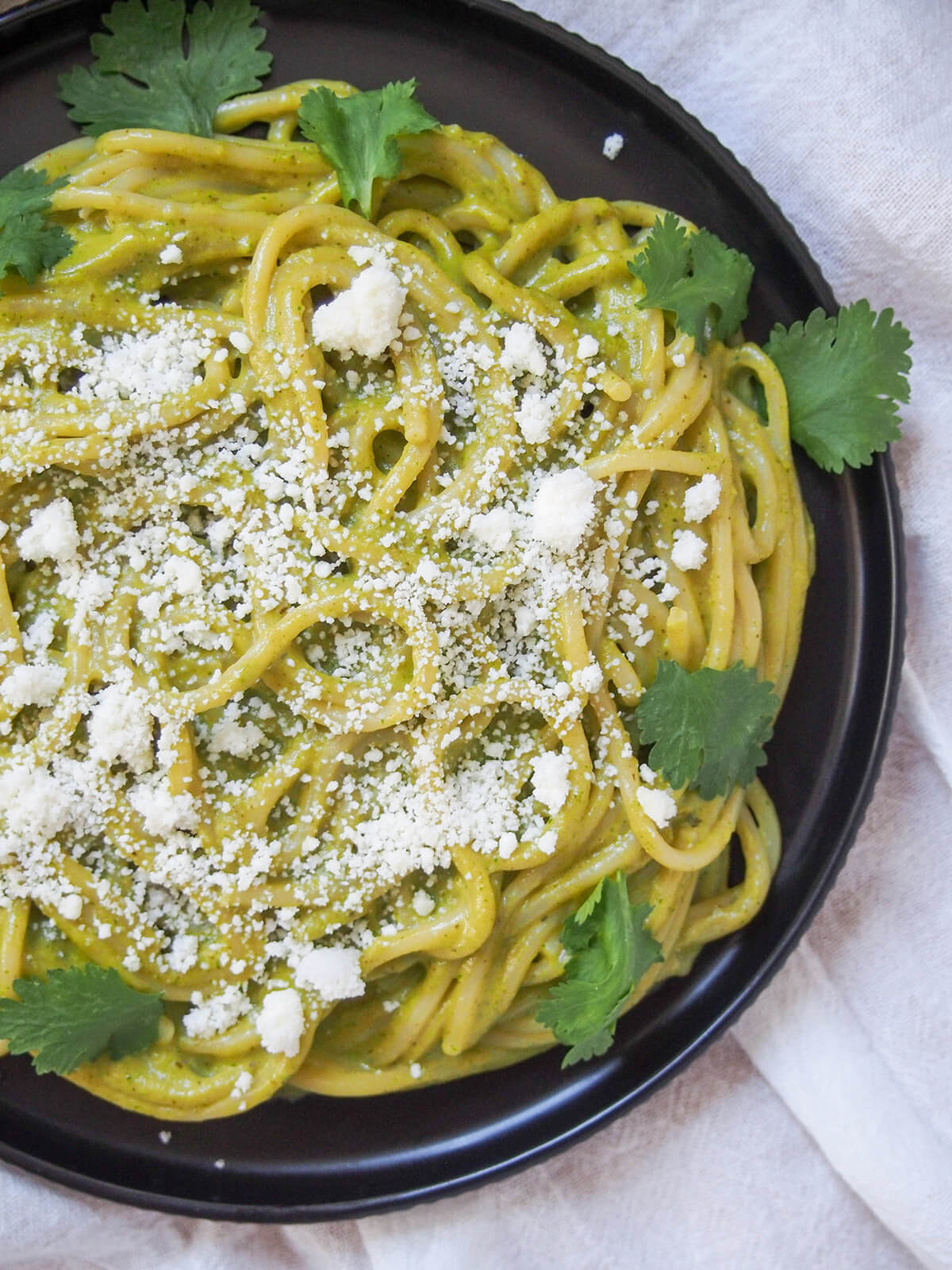 A close-up view of a plate of Espagueti Verde, Mexican green spaghetti, highlighting the creamy texture and inviting appearance of the dish.