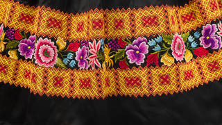 Detail of satin skirt with chain stitch and floral motif embroidery