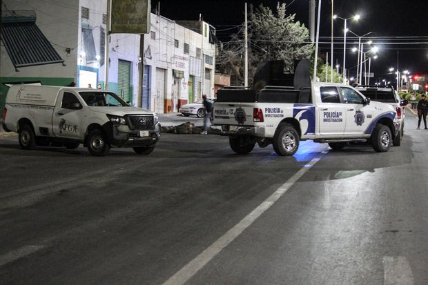 Members of the investigative police stand next to bodies wrapped in blankets and covered with duct tape left by unknown persons on a street in Fresnillo, Zacatecas, Mexico, May 7, 2024, highlighting the severity of the situation in the area.
