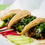 Tacos on a plate with lime and radish