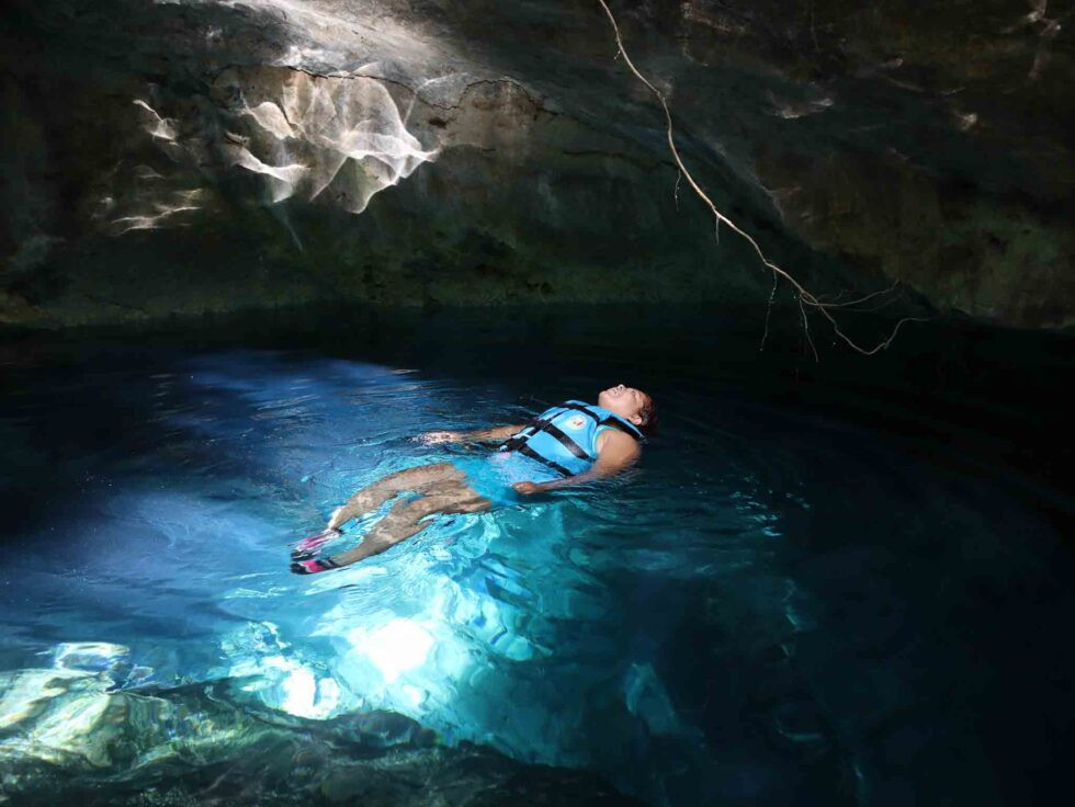Friends swimming in a cenote, capturing a surreal and magical moment with natural blue water