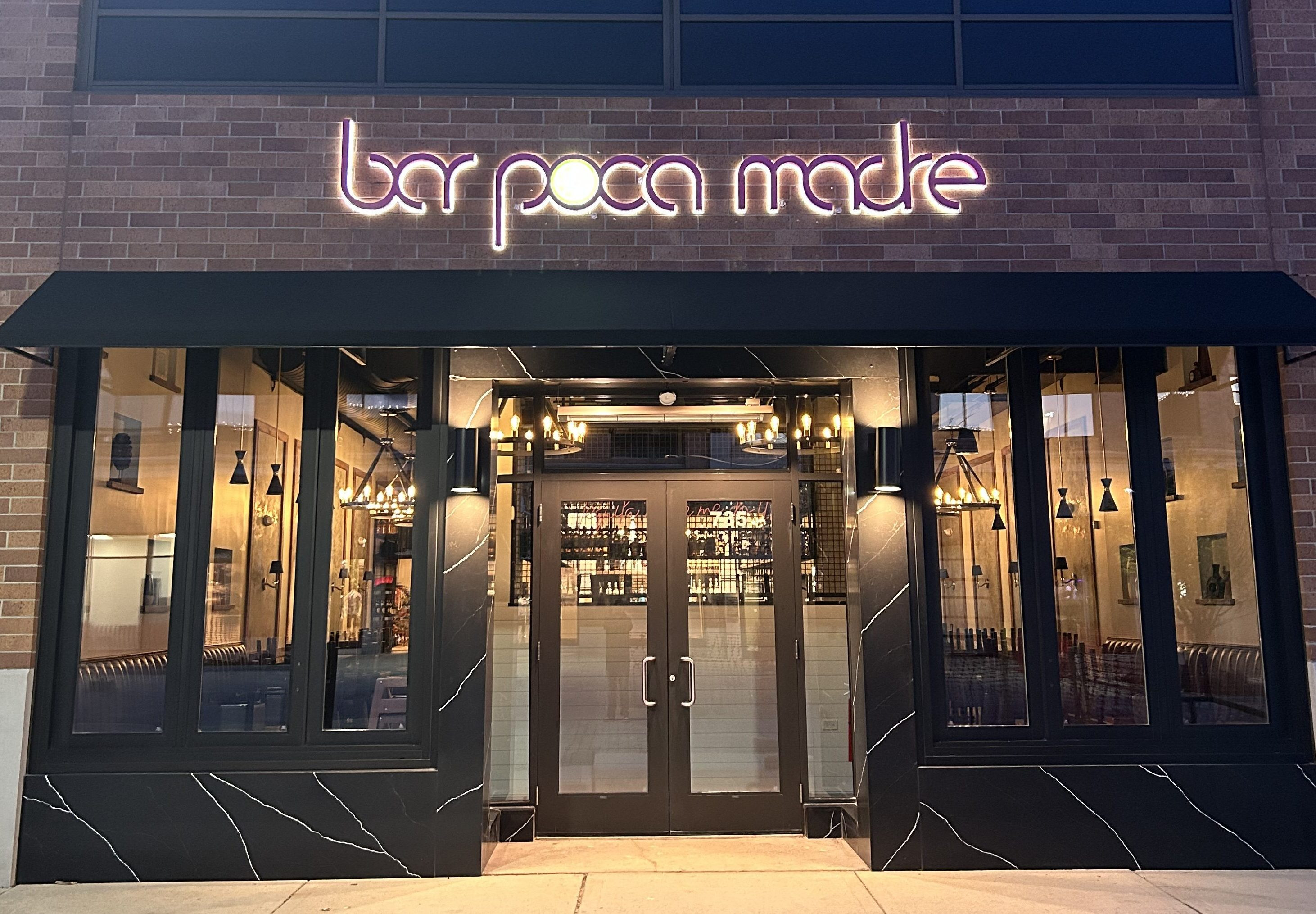 Bar Poca Madre front entrance, lit warmly and invitingly, showcasing its modern design