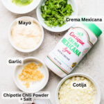 Ingredients needed to make elote, including corn, mayonnaise, crema, cotija cheese, lime, cilantro, and chili powder