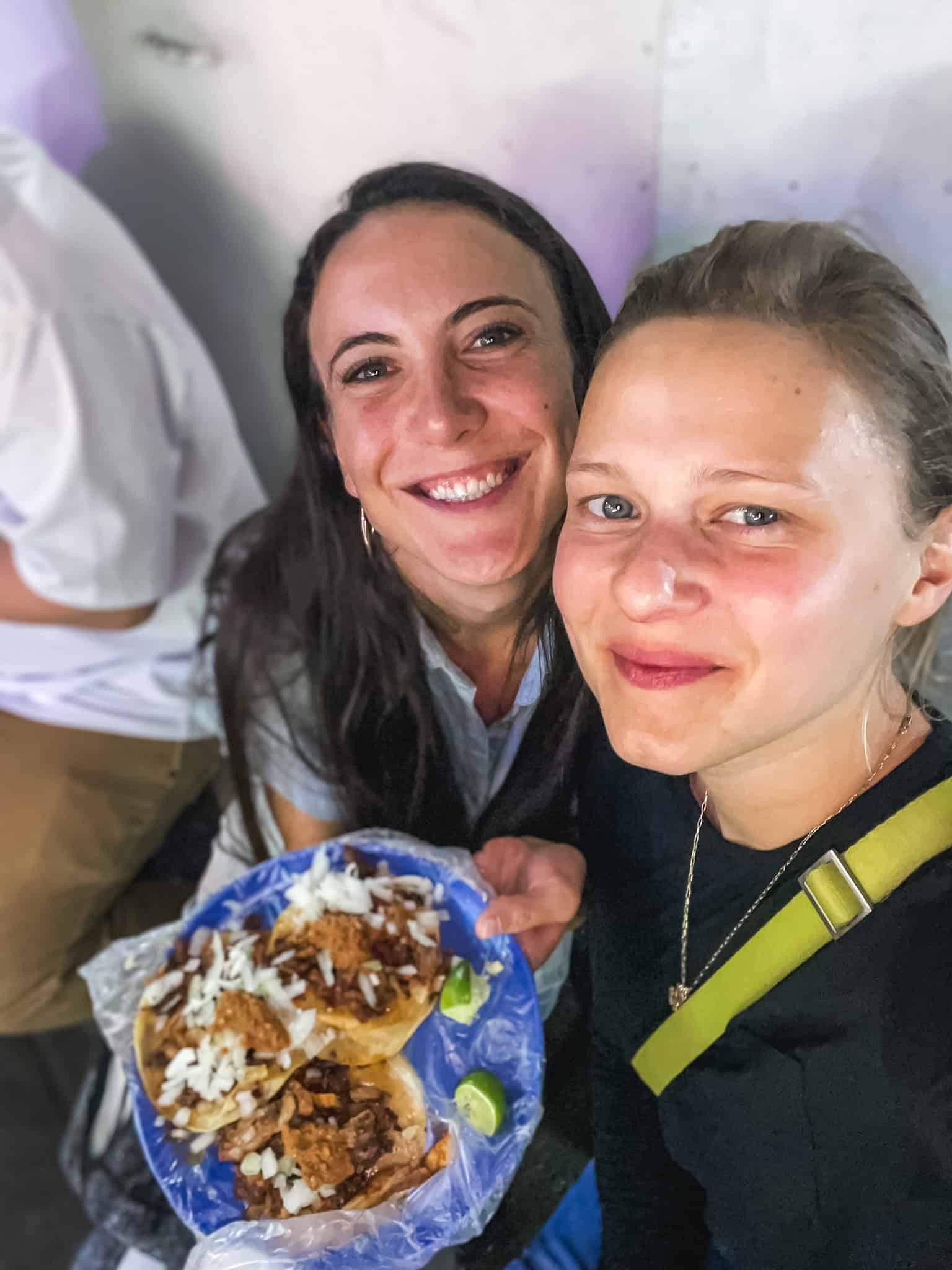 two young women eating three street food tacos for is it safe in mexico city
