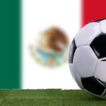 A soccer ball in front of the Mexican flag