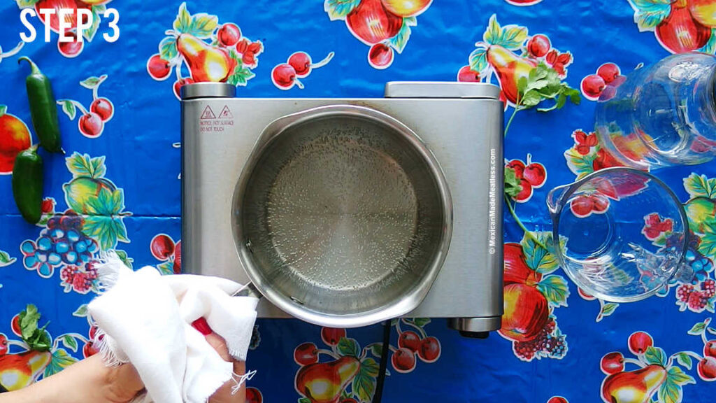Boiling water with white vinegar to create the pickling brine for Mexican carrots, emphasizing the simplicity and essential nature of the brine.