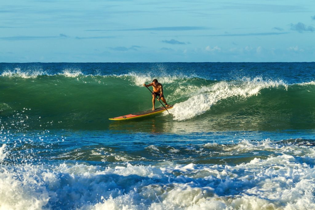 man paddling on paddle board with ocean waves