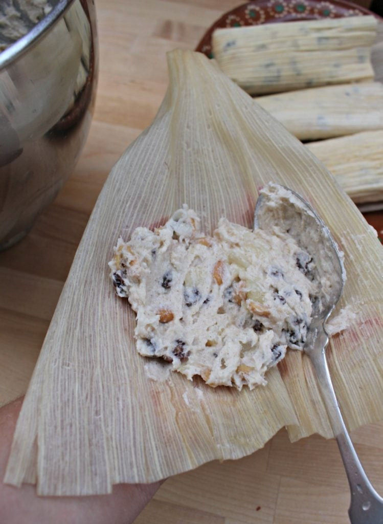 Assembling sweet tamales by spreading masa on corn husk