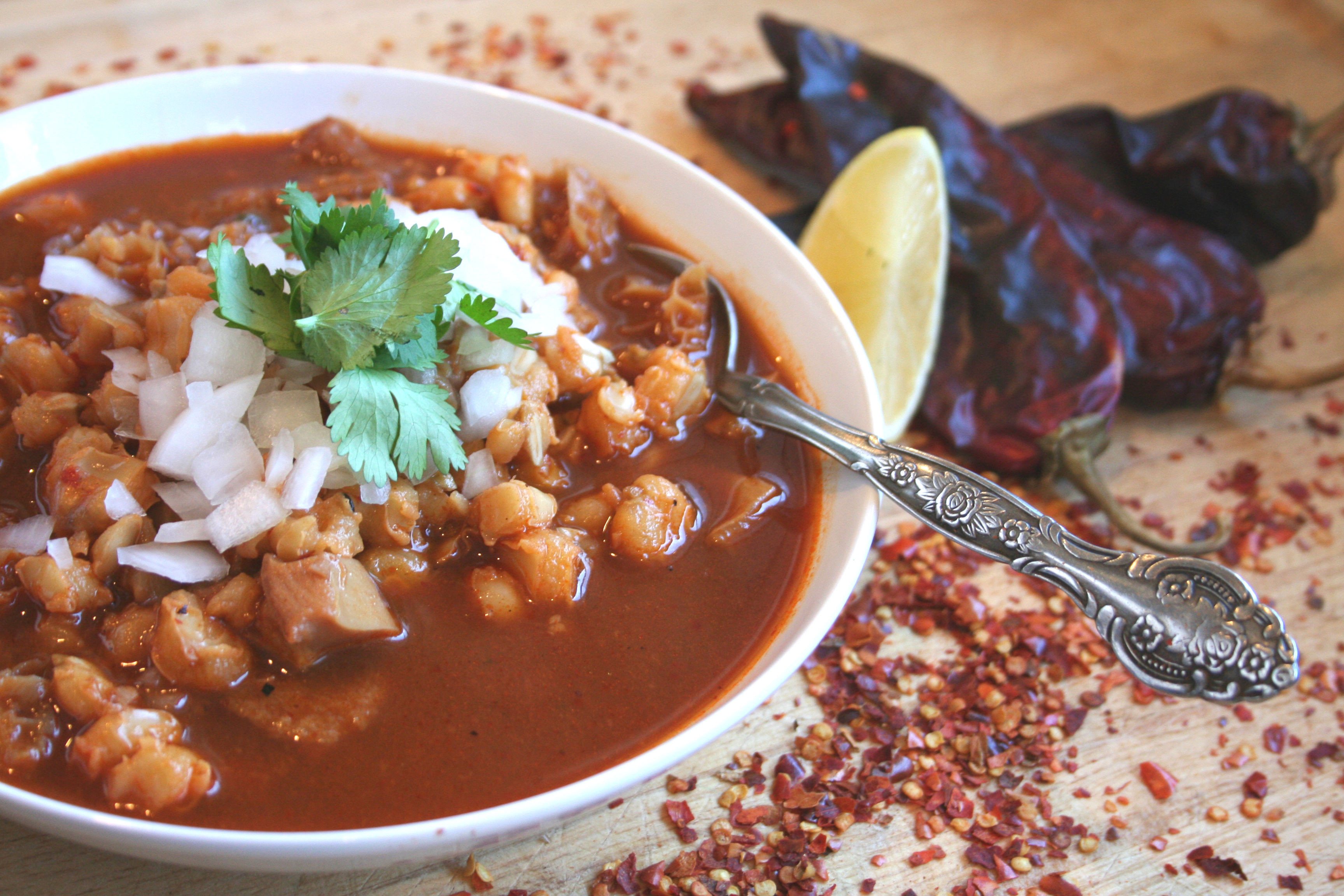 Menudo in a bowl with traditional garnishes like cilantro, onions, and lime