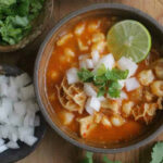 Ingredients for menudo preparation, including beef tripe, hominy, and dried chili peppers.