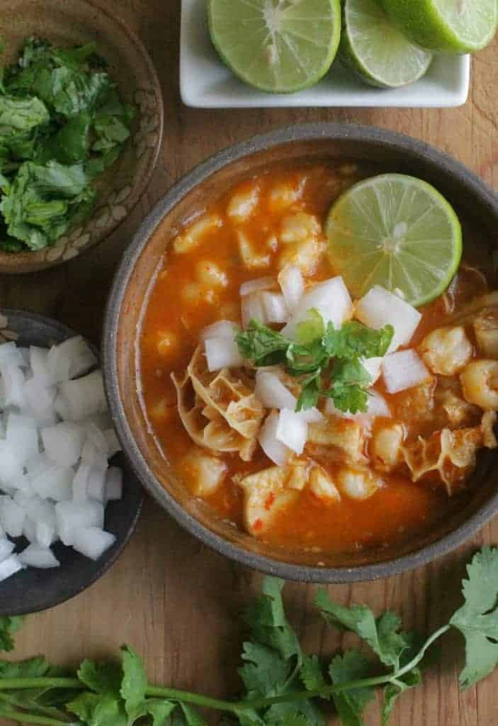 Ingredients for menudo preparation, including beef tripe, hominy, and dried chili peppers.