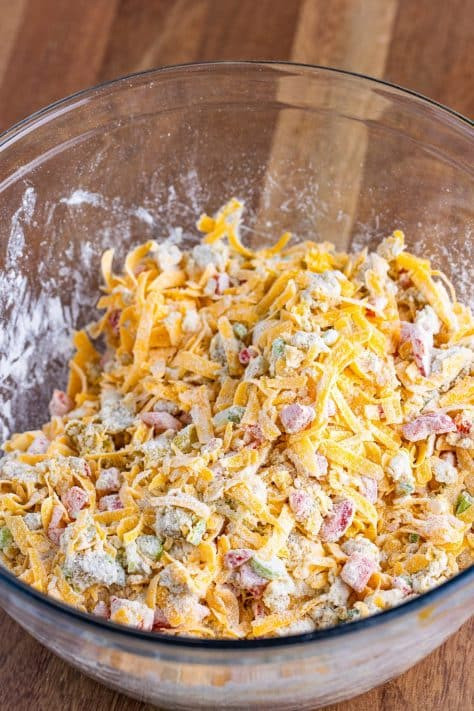 A baking dish with cornmeal, flour, cheese, green onions, green bell pepper, and canned green chili peppers
