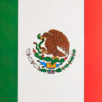 A close-up of the Mexican flag's emblem, showcasing the eagle devouring a serpent on a cactus, symbolizing the Aztec legend and national identity.
