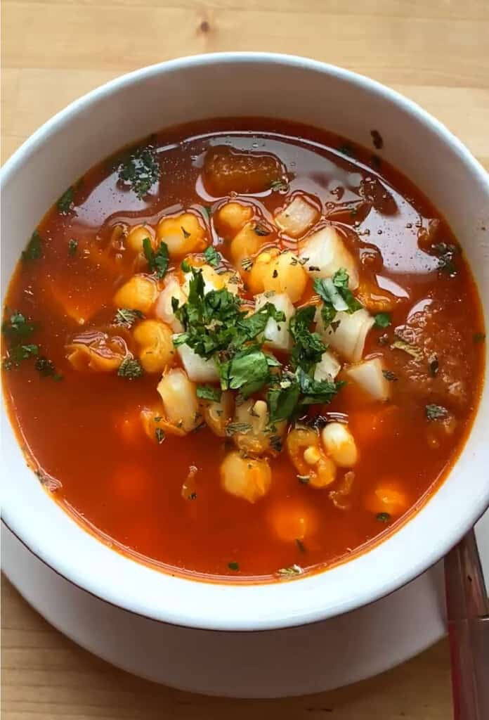 Mexican menudo in a bowl topped with cilantro.