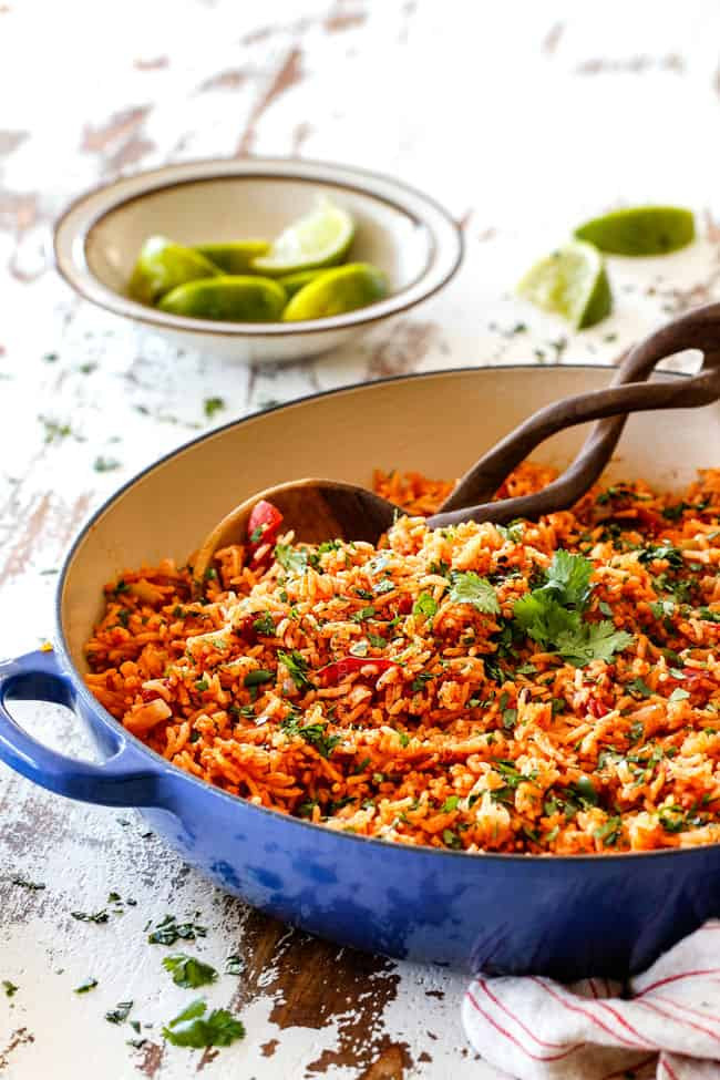 Authentic Mexican rice served with lime wedges in a blue skillet, showcasing its vibrant color and texture.