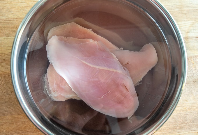Brining chicken breasts in a bowl
