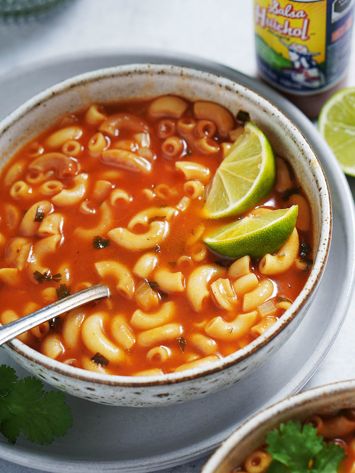Bowl of Mexican Sopita with lime slices, cilantro, and hot sauce