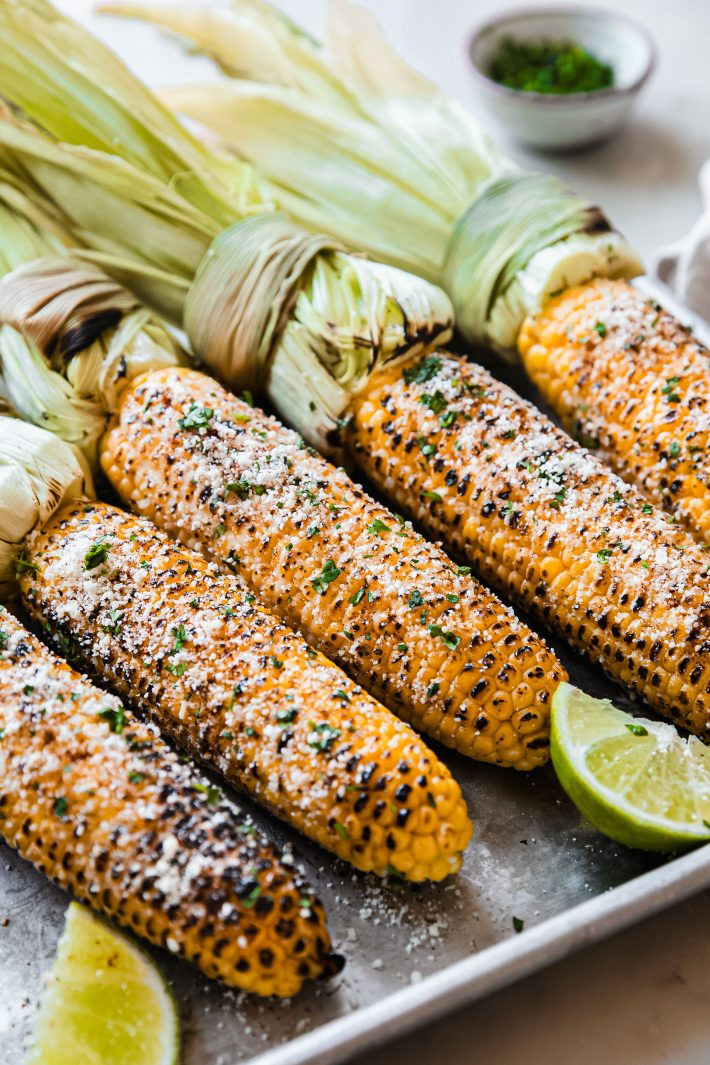 Elotes topped with chili powder, cheese and cilantro