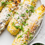 Mexican street corn on a white plate topped with cilantro and cotija