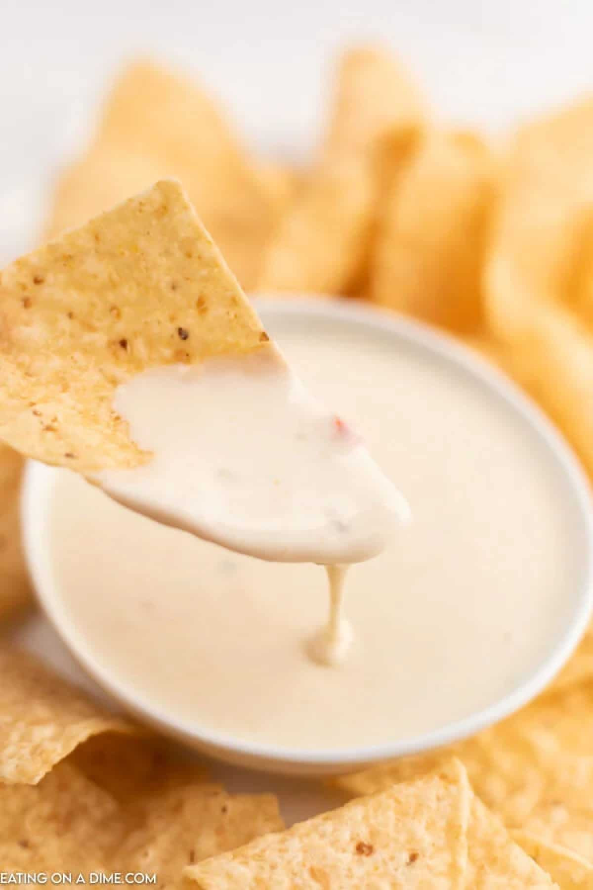 Tortilla chip dipped in a bowl of white queso dip