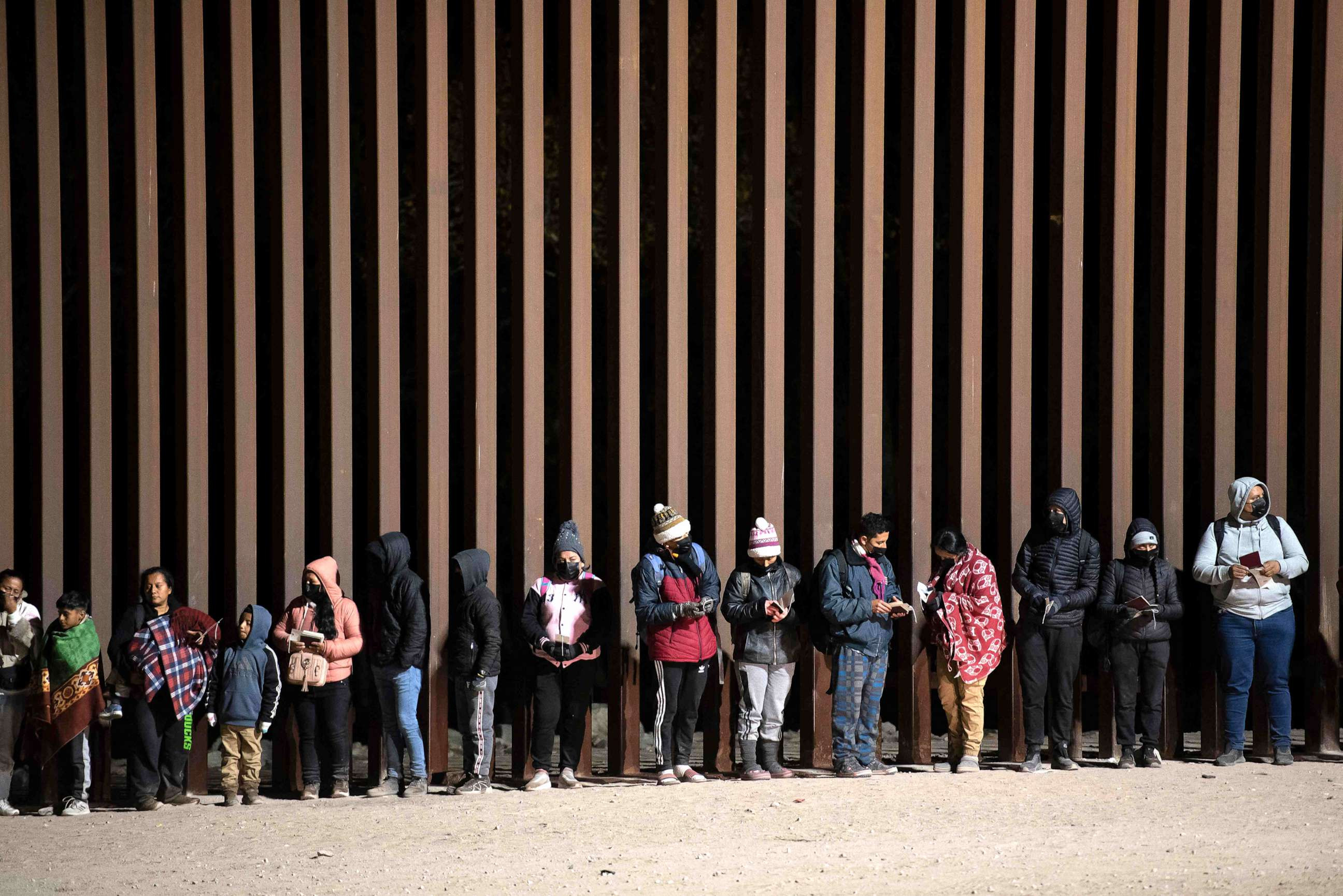 In this Dec. 26, 2022, file photo, asylum-seekers line up to be processed by US Customs and Border Patrol agents at a gap in the US-Mexico border fence near Somerton, Ariz.
