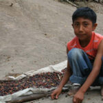 A young boy in Mexico sits with a bowl of beans, showcasing traditional Mexican culture and the challenges some youth face regarding their cultural identity