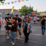 People walk through the streets during a street festival, carrying food and drinks.