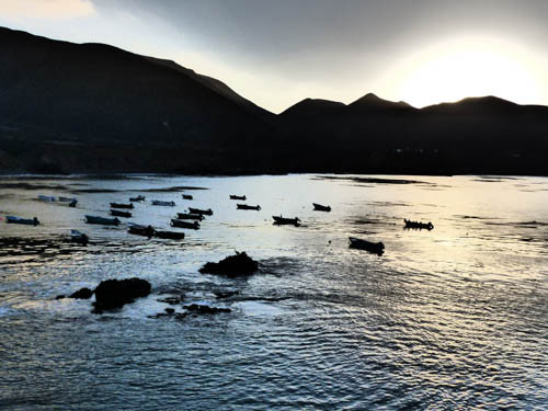 Sunrise over the port in Puerto Santo Tomas, a breathtaking view of the rugged coastline and fishing boats.