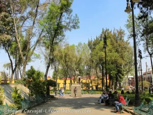 A monument of a national hero in a square with trees and benches