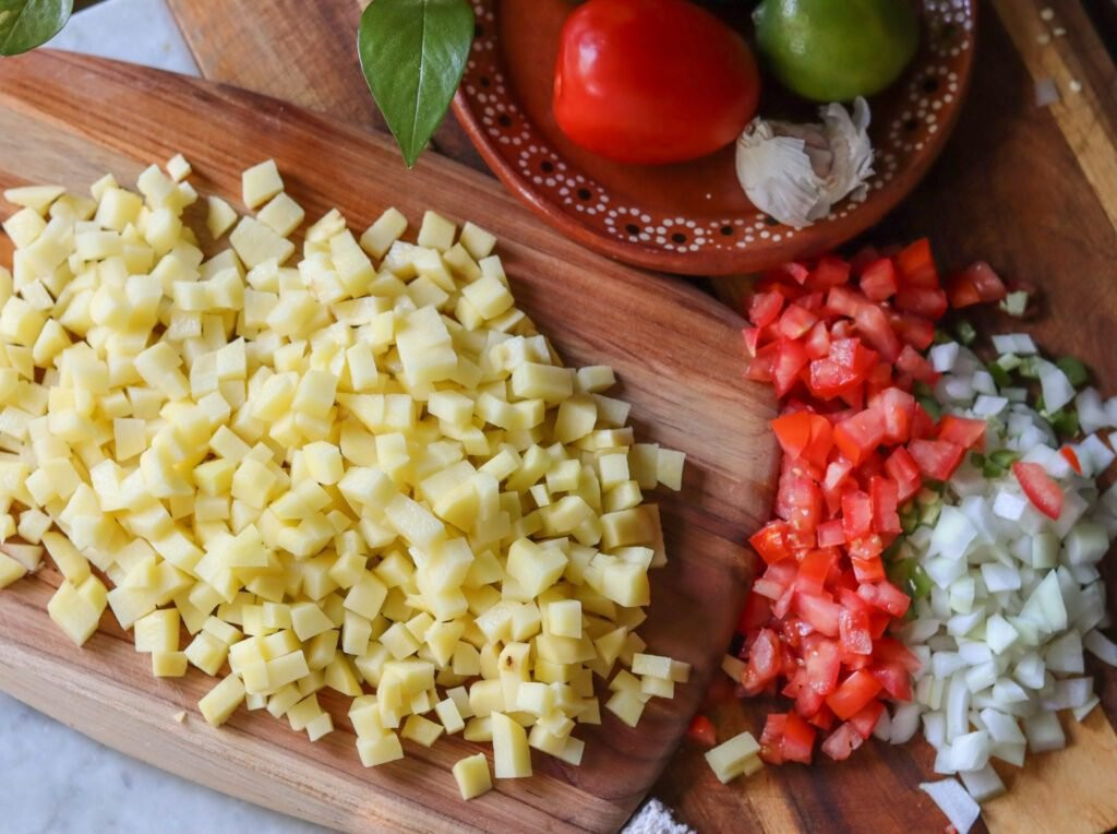 Ingredients for papas a la mexicana on a wooden board.