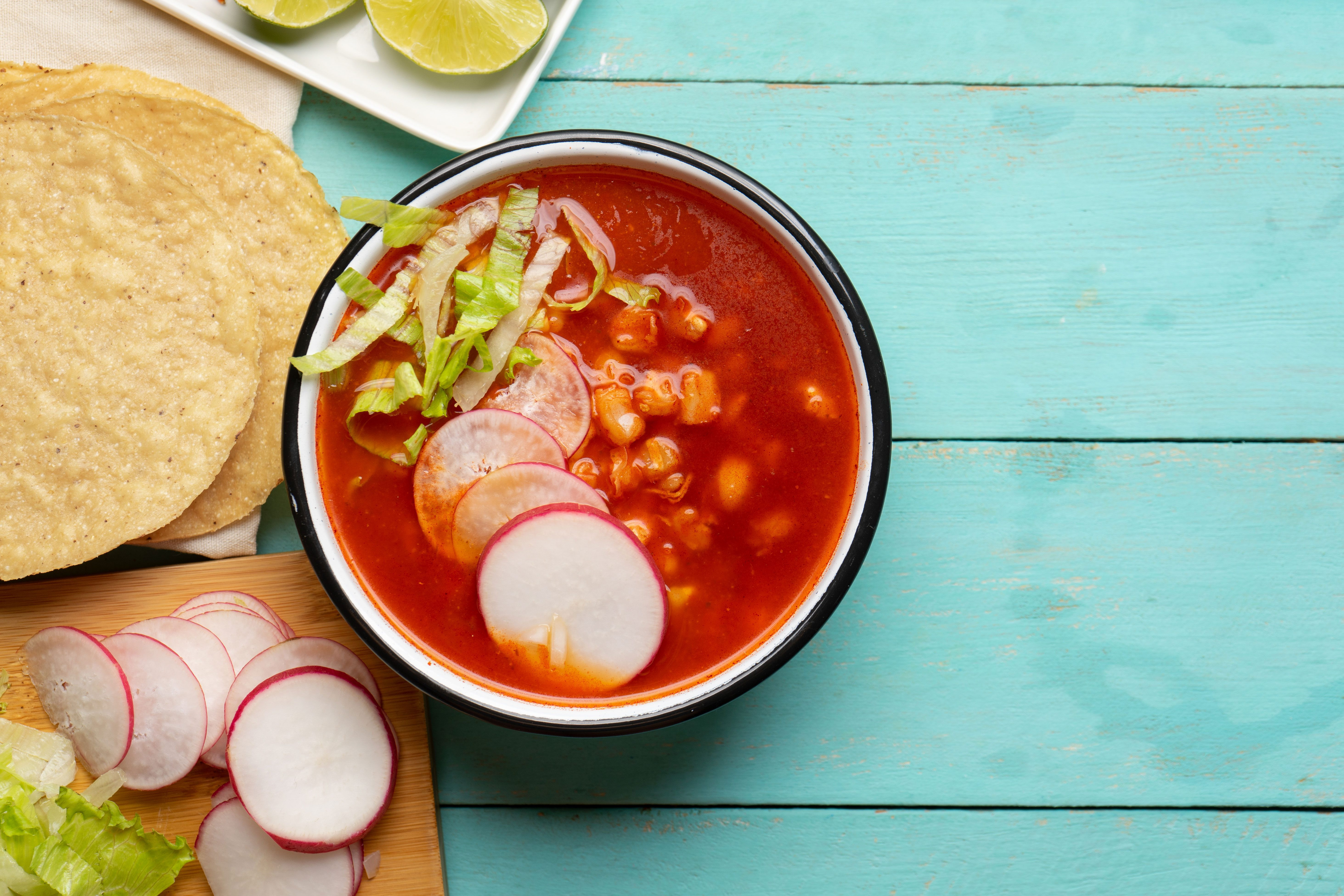 Red soup with beans, radishes and greens next to tortillas