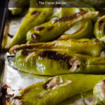 Roasted Hatch chiles with blistered skin on a baking sheet ready to be used in various dishes.