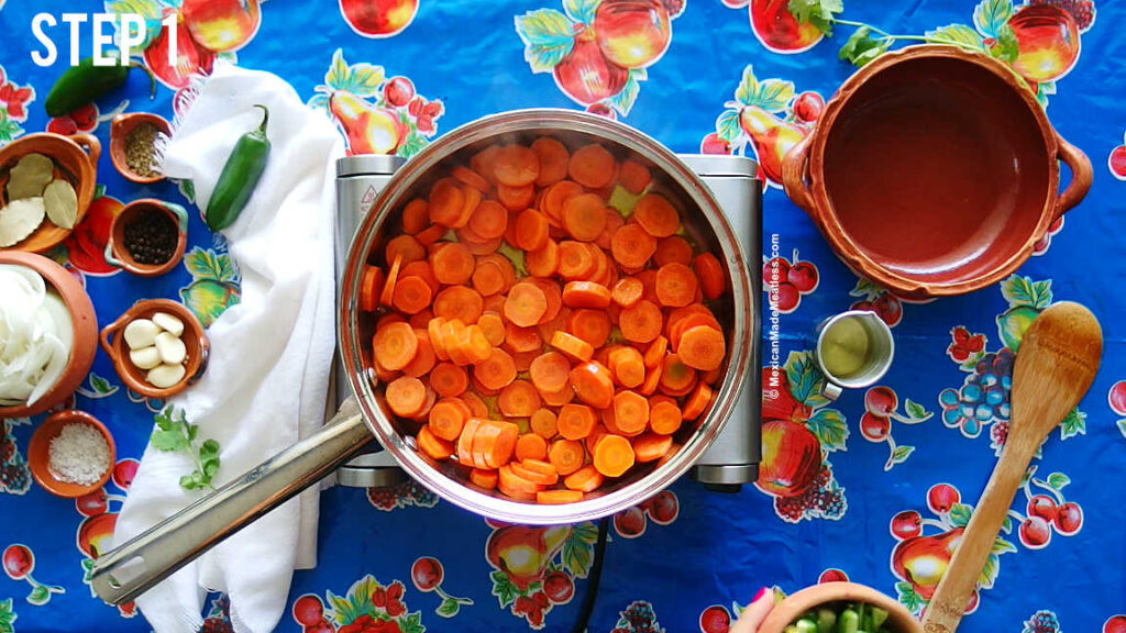 Sautéing sliced carrots in a stainless steel pan as the first step in making spicy Mexican pickled carrots, highlighting the vibrant colors and textures.
