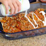 Mexican table cream drizzled in a lasagna with meat sauce
