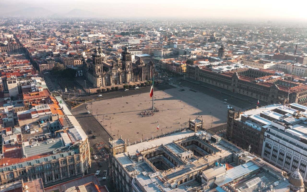 An aerial shot of Plaza de la Constitucion in Mexico with a large Mexican flag in the center.