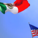 A Mexican and American flag on flagpoles, representing the complex relationship between the two countries.