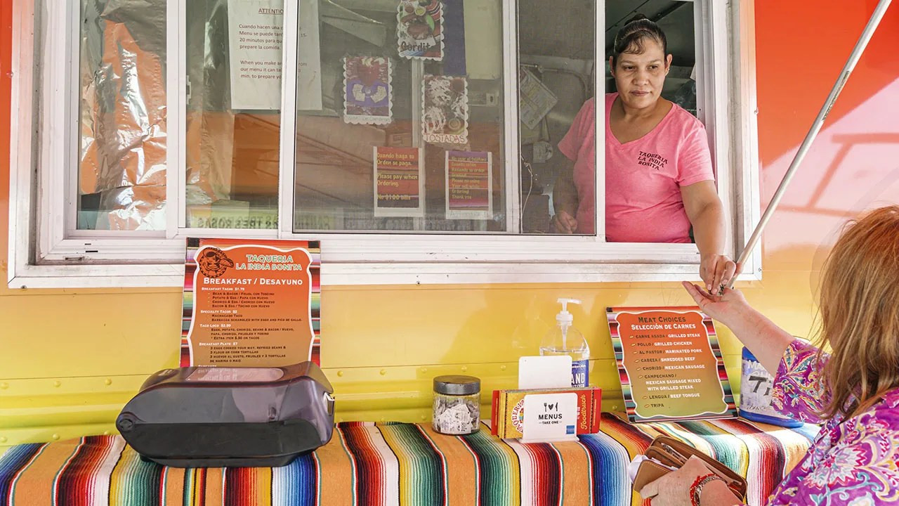 A customer enjoys a meal at a vibrant Mexican food truck in Florida, illustrating the widespread popularity of Mexican cuisine in the U.S.