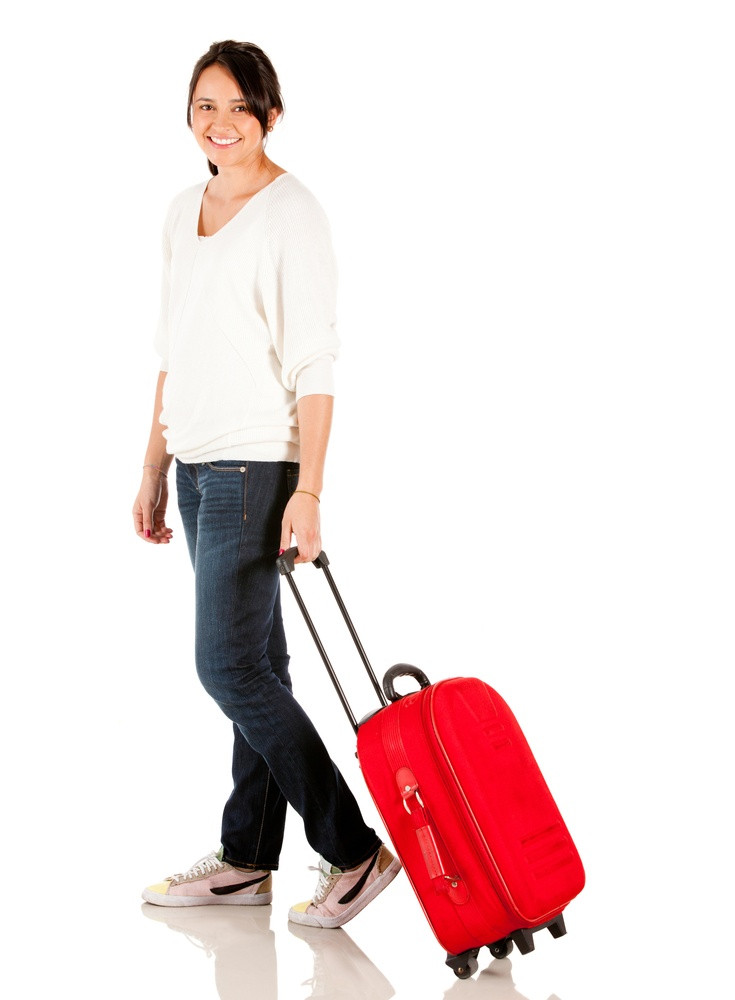 Woman in airport with luggage looking happy