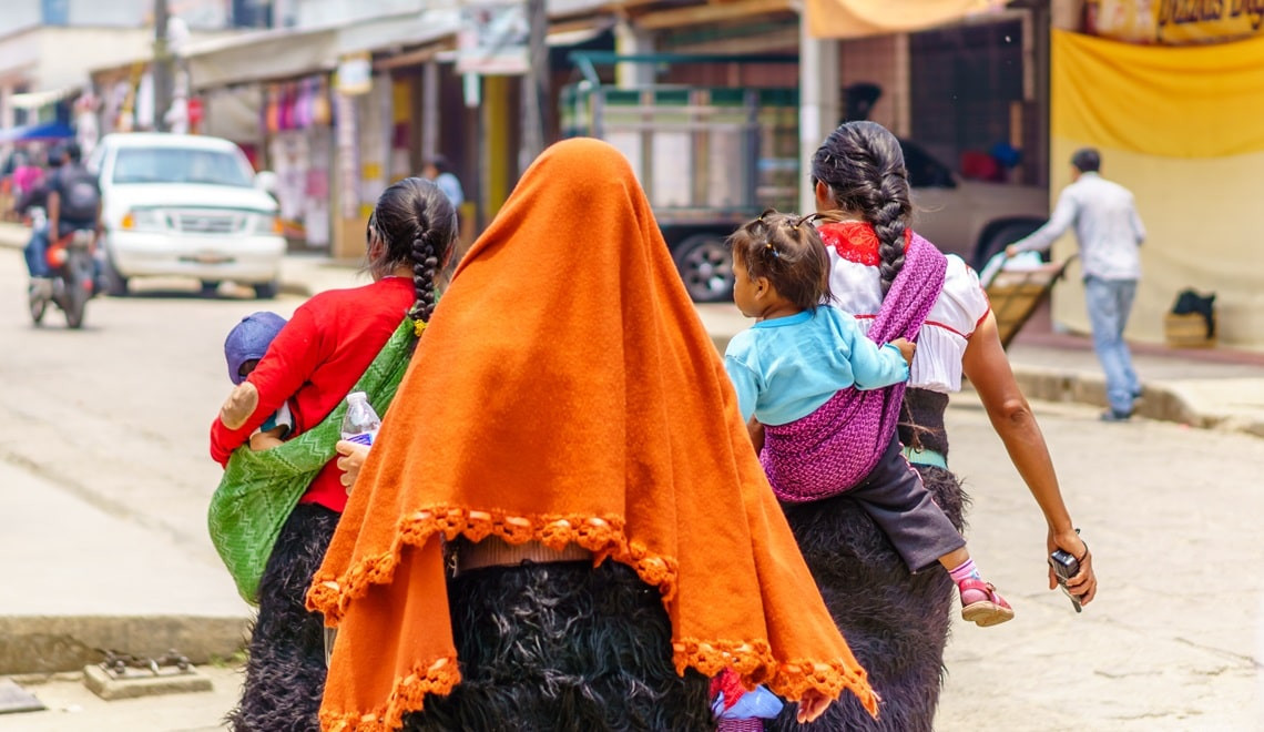 A vibrant street scene in Mexico with colorful buildings and people walking.